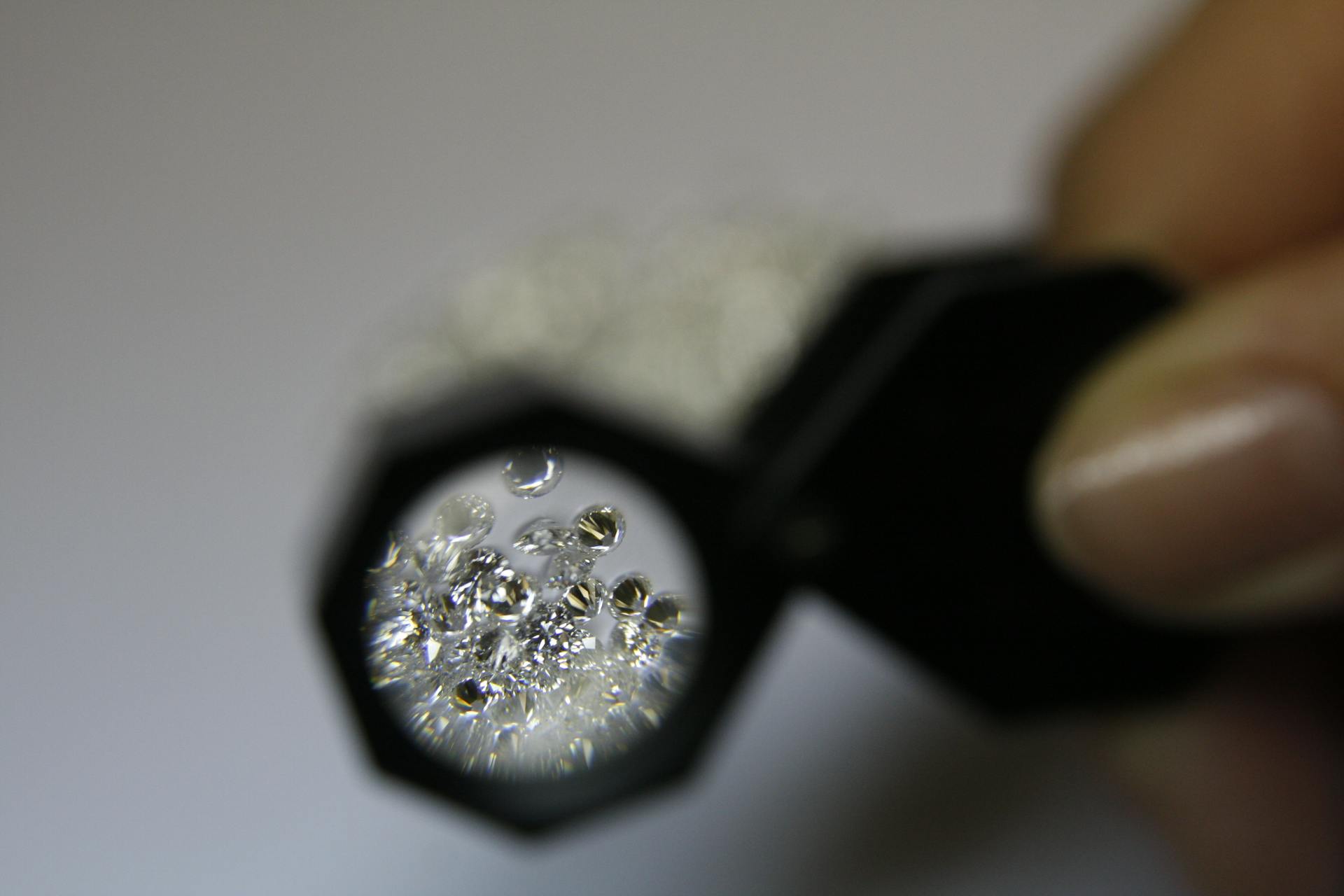 Diamond dealer examining certified loose diamonds through a jeweller's loupe